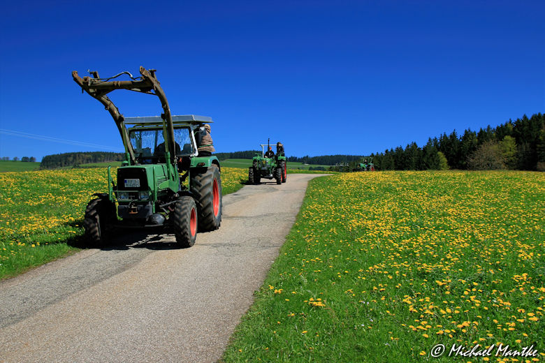 Traktoren auf Wanderweg zwischen Wiesen