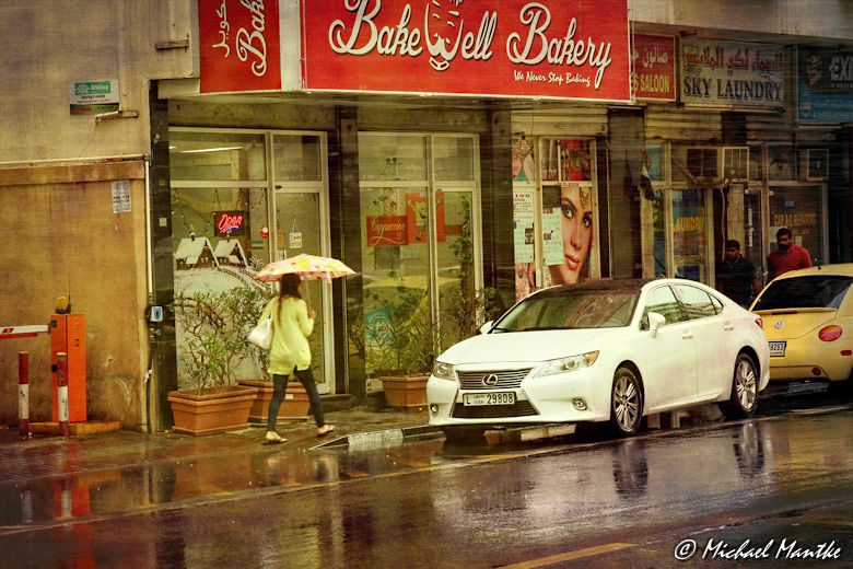Dubai im Regen Fußgänger mit Schirm und Auto