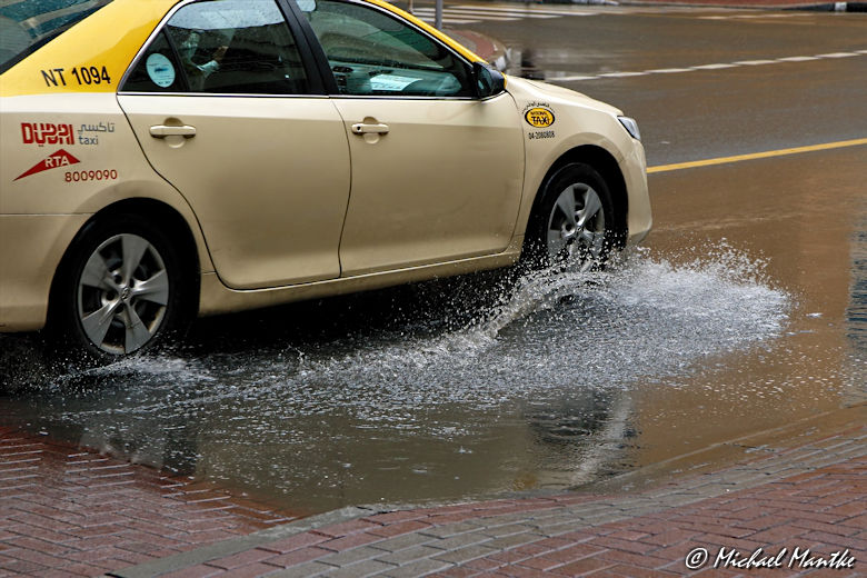 Dubai im Regen Taxi fährt durch Pfütze